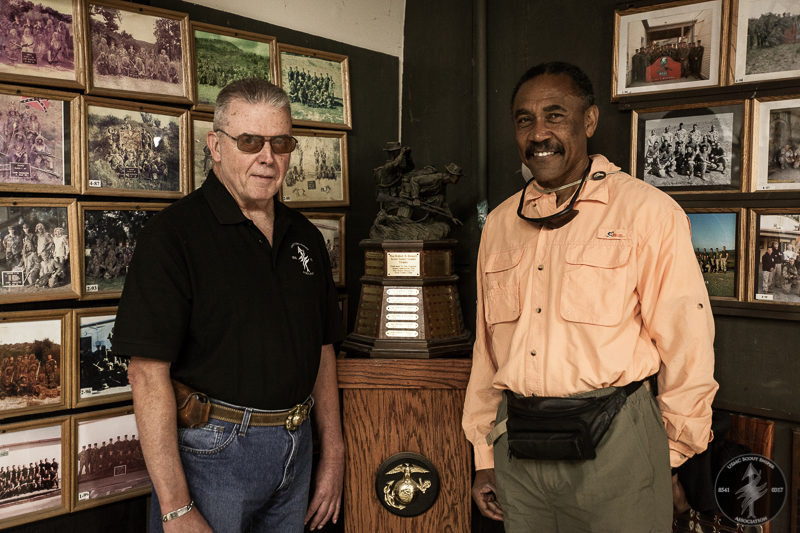 Vietnam Era Marine Scout Snipers Bob Depp and Artfield Davis pose in front of the Scout Sniper Leader Trophy. The trophy was inspired by Mr. Depp's Photograph.